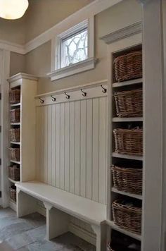 a white bench sitting in the middle of a room with lots of baskets on it