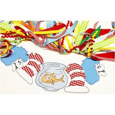 an assortment of colorful ribbons and decorations on a white table with a fish in a jar