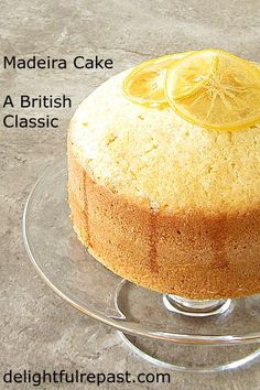 a cake sitting on top of a glass plate covered in frosting and lemon slices