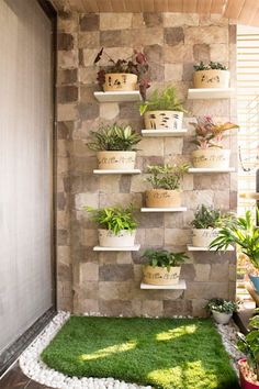 a wall with plants on it and grass in the middle, next to a potted planter