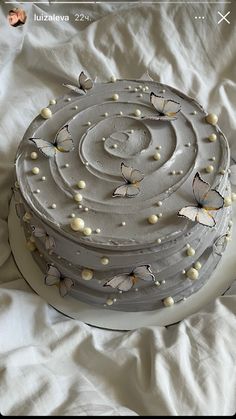 a cake with butterflies on it sitting on a white sheet covered tablecloth in the shape of a spiral