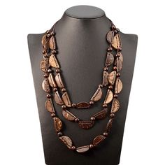 This brown wooden necklace is a unique accessory that will add a touch of earthy and natural charm to any outfit. The necklace is made up of three layers of different elements that are intertwined beautifully to create a one-of-a-kind piece. The first type of element consists of brown wooden beads with a diameter of 3-5mm, while the second type of element is made of brown coconut shell crescents. These elements are threaded onto three black textile cords, each with a different perimeter, creatin Coconut Shells, Wooden Bead Necklaces, Artisan Necklace, Brown Necklace, Wooden Necklace, Color Cafe, Bohemian Necklace, Wood Pendant, Necklace Women