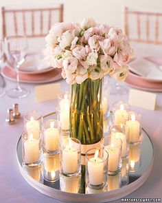 a vase filled with lots of white flowers sitting on top of a table next to candles