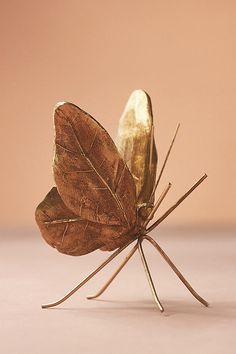 a gold colored butterfly sitting on top of a pink surface with its wings spread out