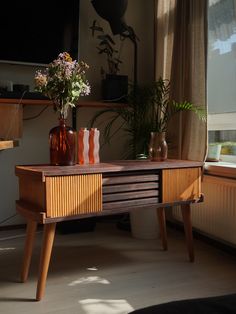 a wooden table with vases and flowers on it in front of a large window