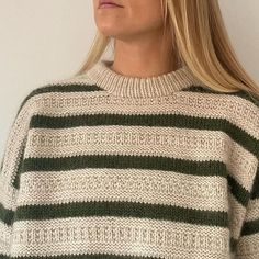 a woman with blonde hair wearing a green and white striped sweater looking off to the side