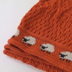 an orange knitted hat with sheep on it