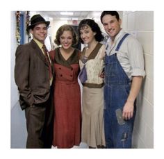 three men and two women are posing for the camera in an office hallway with white walls