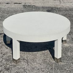 a white coffee table sitting on top of a cement ground next to a parking lot