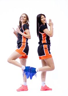 two young women in sports uniforms are posing for a photo with their hands up to the side