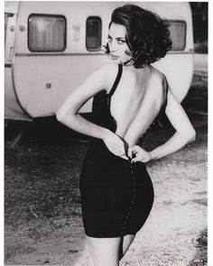 a black and white photo of a woman in front of a camper