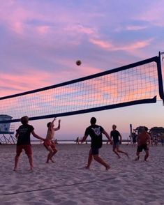 people playing volleyball on the beach at sunset