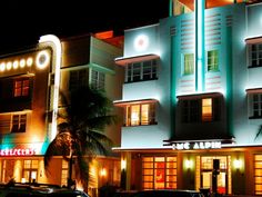 a large white building with neon lights on it's sides and cars parked in front