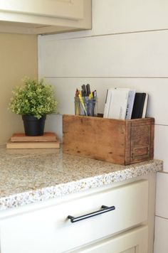 a wooden box sitting on top of a kitchen counter next to a potted plant