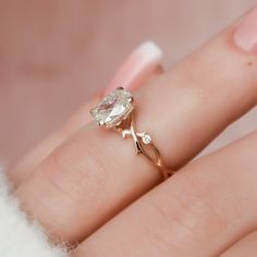 a woman's hand with a ring on it and an oval shaped diamond in the middle