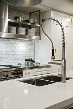 a modern kitchen with stainless steel appliances and white counter tops, along with an island style sink