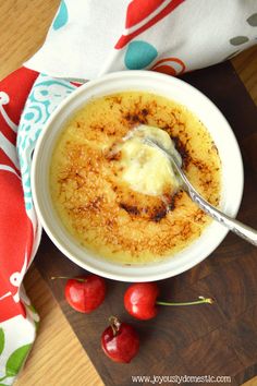 a bowl filled with food next to cherries on a cutting board and a napkin