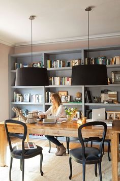 a woman sitting at a table in front of a book shelf