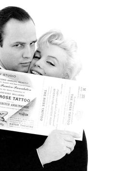 a man and woman hugging each other while holding up a large piece of paper with the words rose tattoo on it