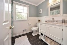 a bathroom with gray walls and white cabinets