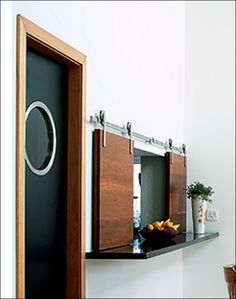 an open door to a bathroom next to a table with flowers and vases on it