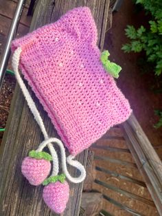 a pink crocheted bag sitting on top of a wooden bench