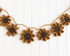 crocheted sunflowers are hanging from a string on a white wall,