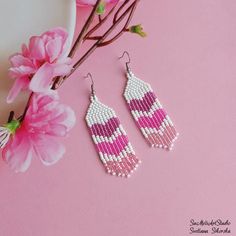 the pink and white beaded earrings are next to a flower on a pink background