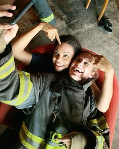 two children sitting in a chair with their arms around each other and one pointing at the camera