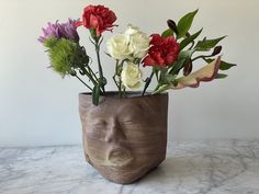 a vase filled with flowers sitting on top of a marble counter next to a white wall