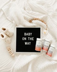 the baby on the way sign is next to two jars and a pair of slippers