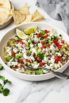 a white bowl filled with salsa and tortilla chips on top of a marble counter