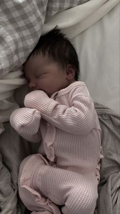 a baby sleeping on top of a bed covered in blankets