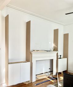 an empty living room with white walls and wood flooring in the foreground is a fireplace