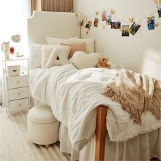 a bed with white sheets and pillows in a bedroom next to a window filled with pictures