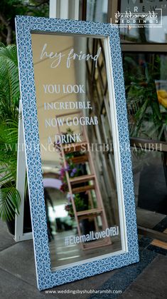 a blue and white frame sitting on top of a sidewalk next to a planter