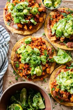 four tacos with meat, lettuce and salsa on top next to a bowl