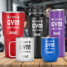 thermos cups are sitting on a table with personalized names and colors in front of them