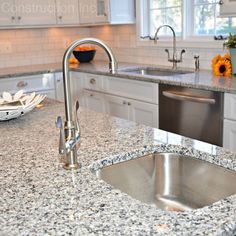 a kitchen with granite counter tops and stainless steel sink faucet in the center