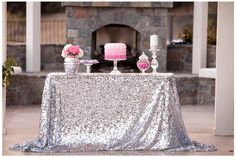 a table topped with a pink cake and two white candles next to a fire place