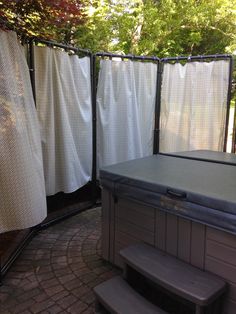 a hot tub sitting next to a wooden bench on top of a brick floored patio