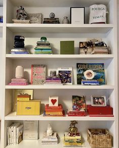 a book shelf filled with lots of books and other items on top of white shelves