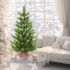 a living room with a christmas tree in the corner and candles on the coffee table