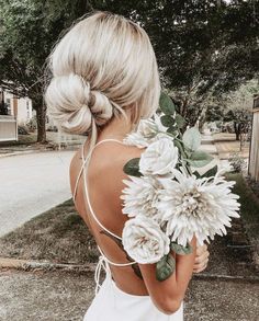 a woman with blonde hair holding flowers in her hand