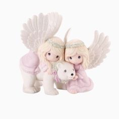 two figurines that are holding a teddy bear and wearing angel wings on top of each other