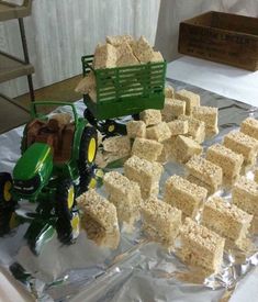 a green tractor and some food on top of a tin foil covered table with other items