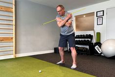 an older man is playing golf in his home gym