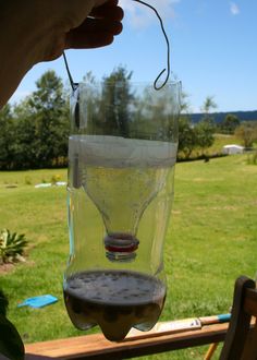 a person holding up a glass hanging from a string in front of a grassy field