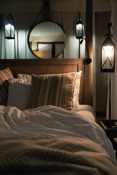 a bed with white sheets and pillows next to a round mirror on the wall above it