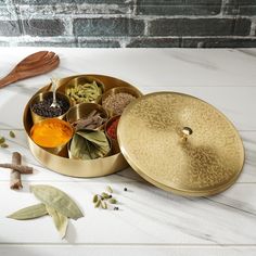 an assortment of spices sits in a brass container